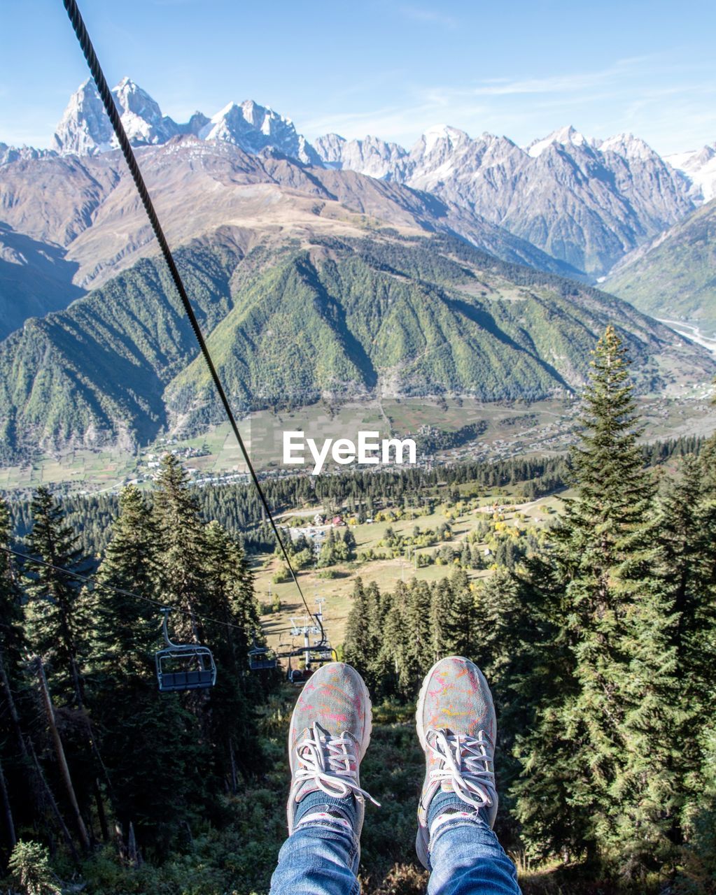 Human legs on cable railway above mountains 