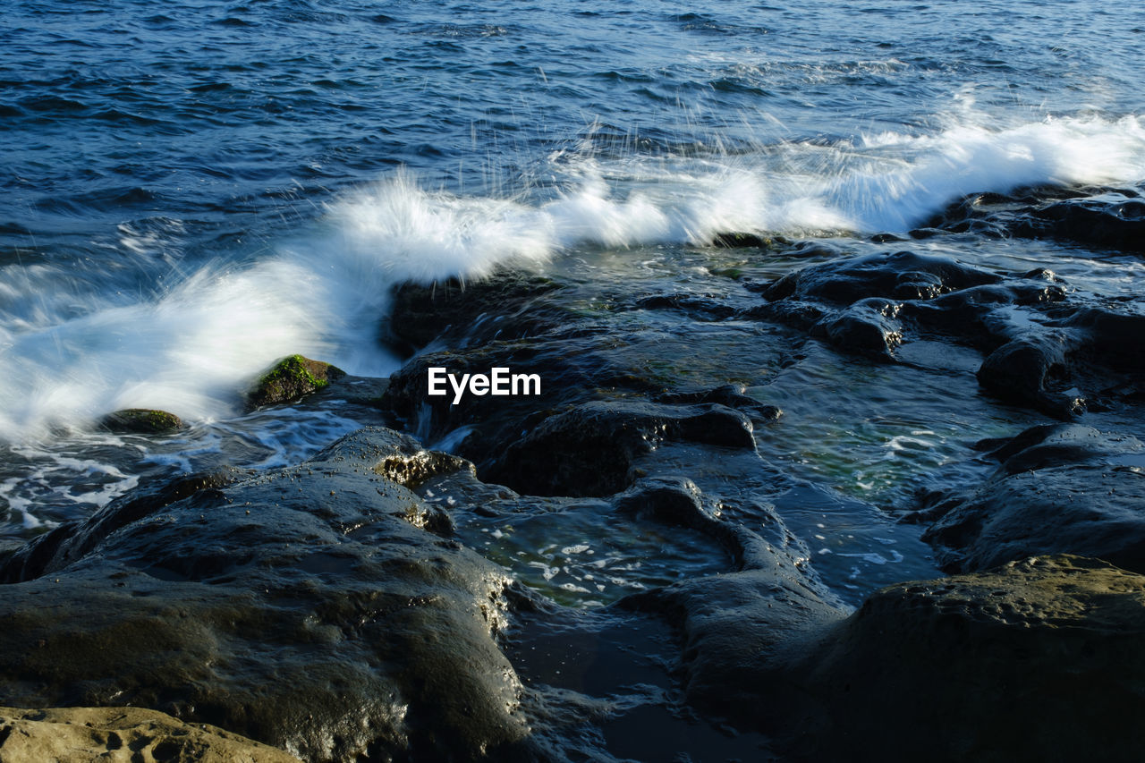 water, sea, motion, ocean, wave, beauty in nature, wind wave, coast, rock, body of water, shore, nature, scenics - nature, land, sports, beach, no people, water sports, power in nature, outdoors, day, splashing, horizon, high angle view, breaking, environment