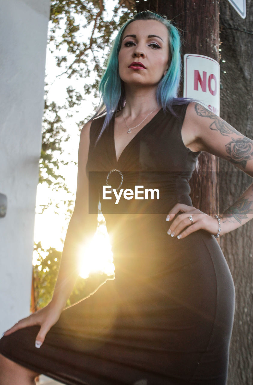 Low angle portrait of female model posing by column during sunset