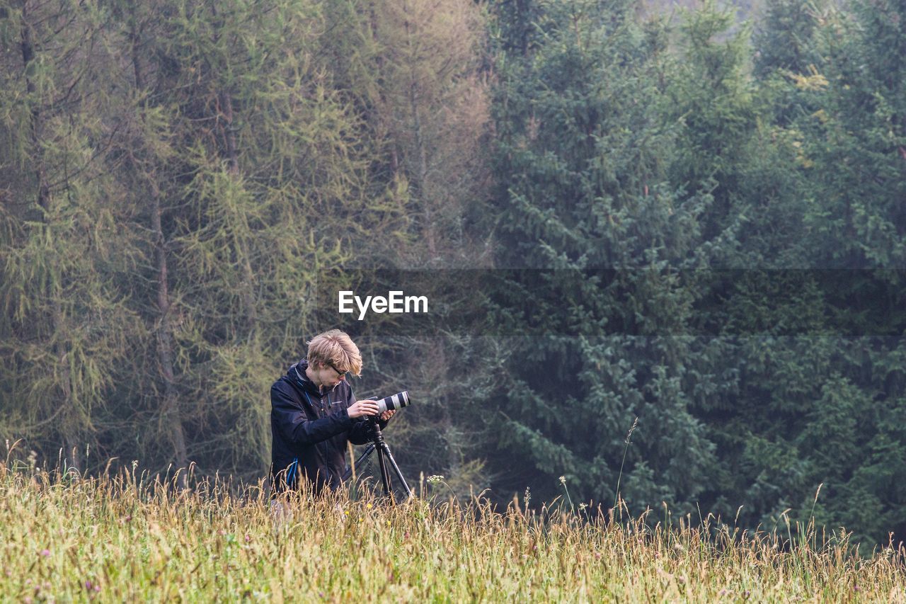 Man with digital camera and tripod in forest