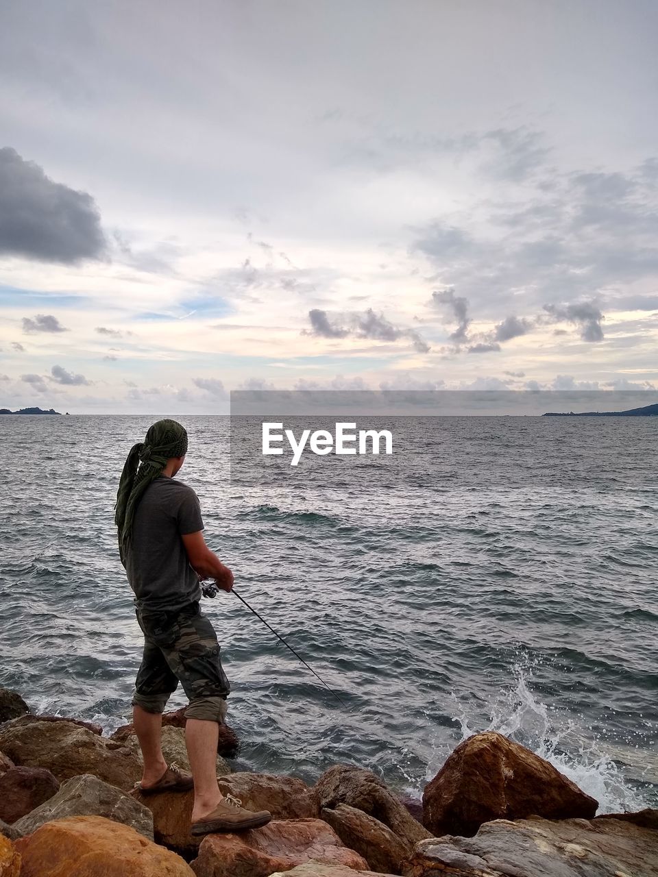 Rear view of man looking at sea against sky