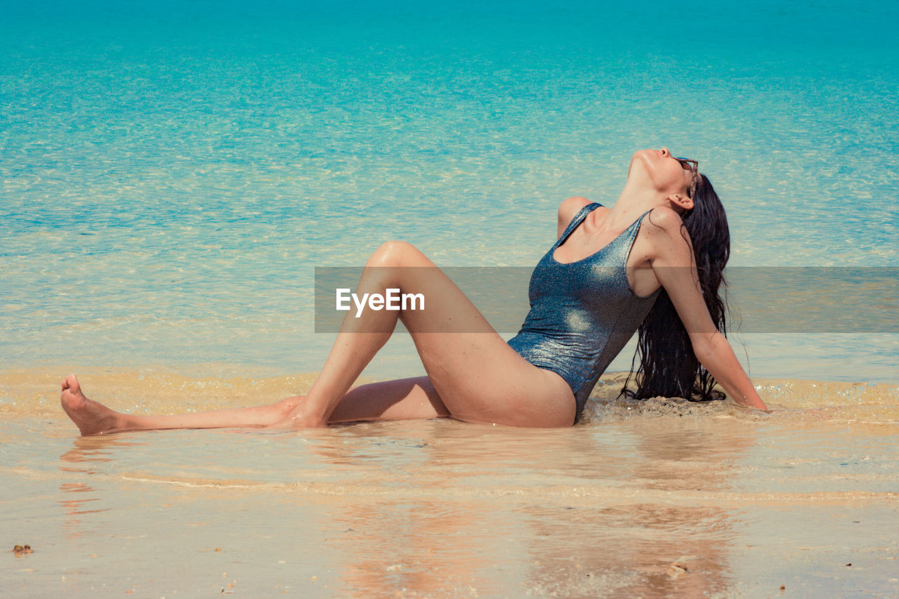 Full length woman wearing swimwear while lying at beach