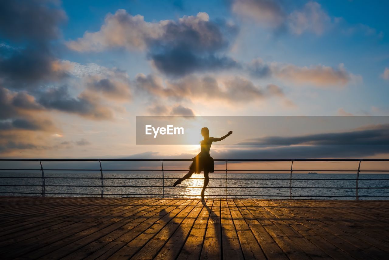 SILHOUETTE WOMAN STANDING ON SEA SHORE AGAINST SKY