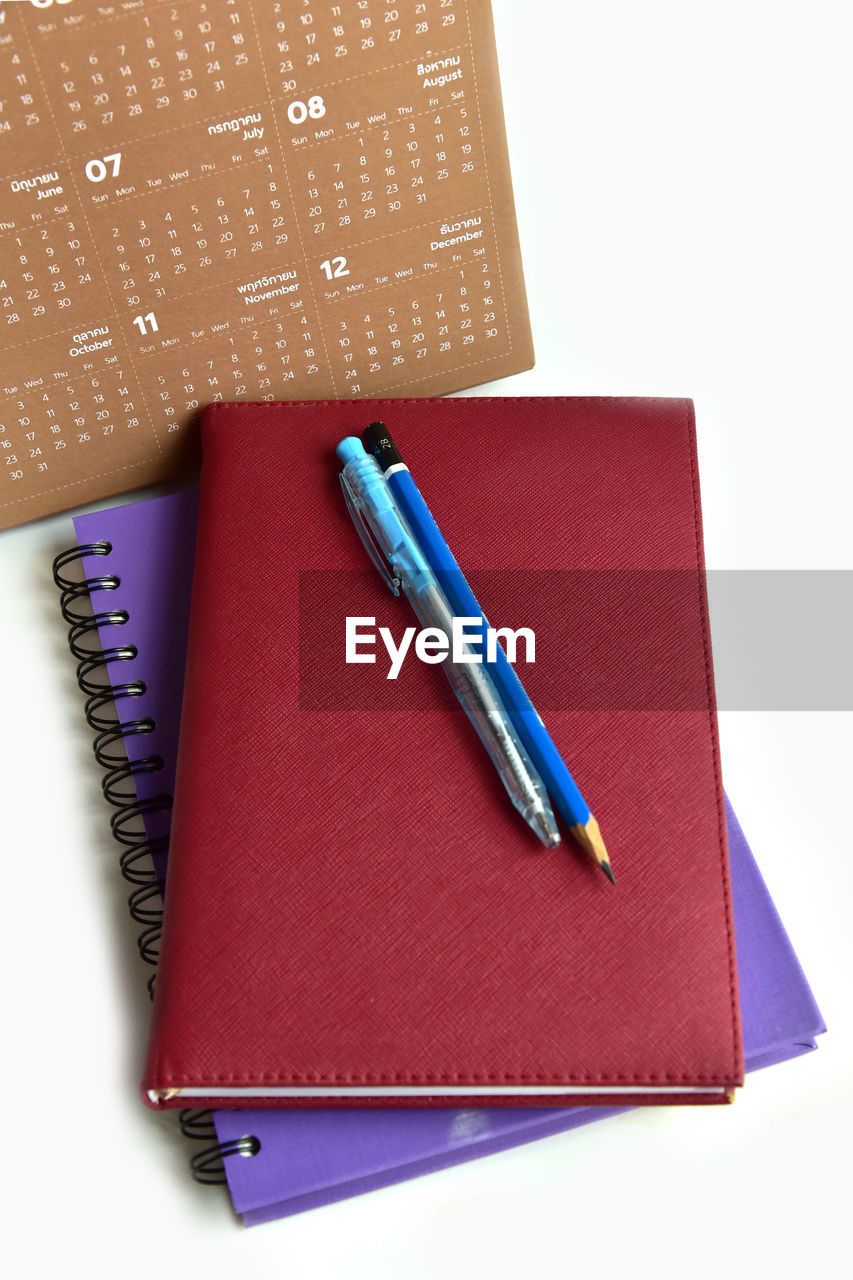 HIGH ANGLE VIEW OF PEN AND BOOK ON PAPER
