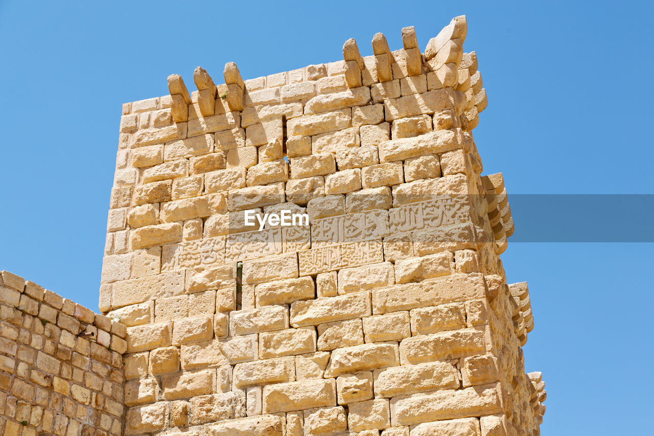 LOW ANGLE VIEW OF STONE WALL AGAINST CLEAR SKY