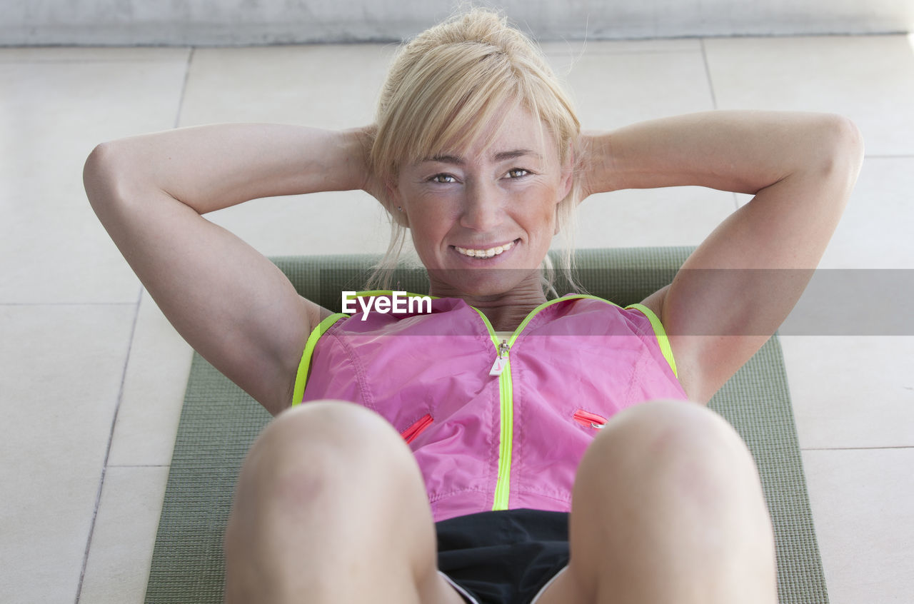 PORTRAIT OF A SMILING YOUNG WOMAN SITTING AGAINST PINK OUTDOORS