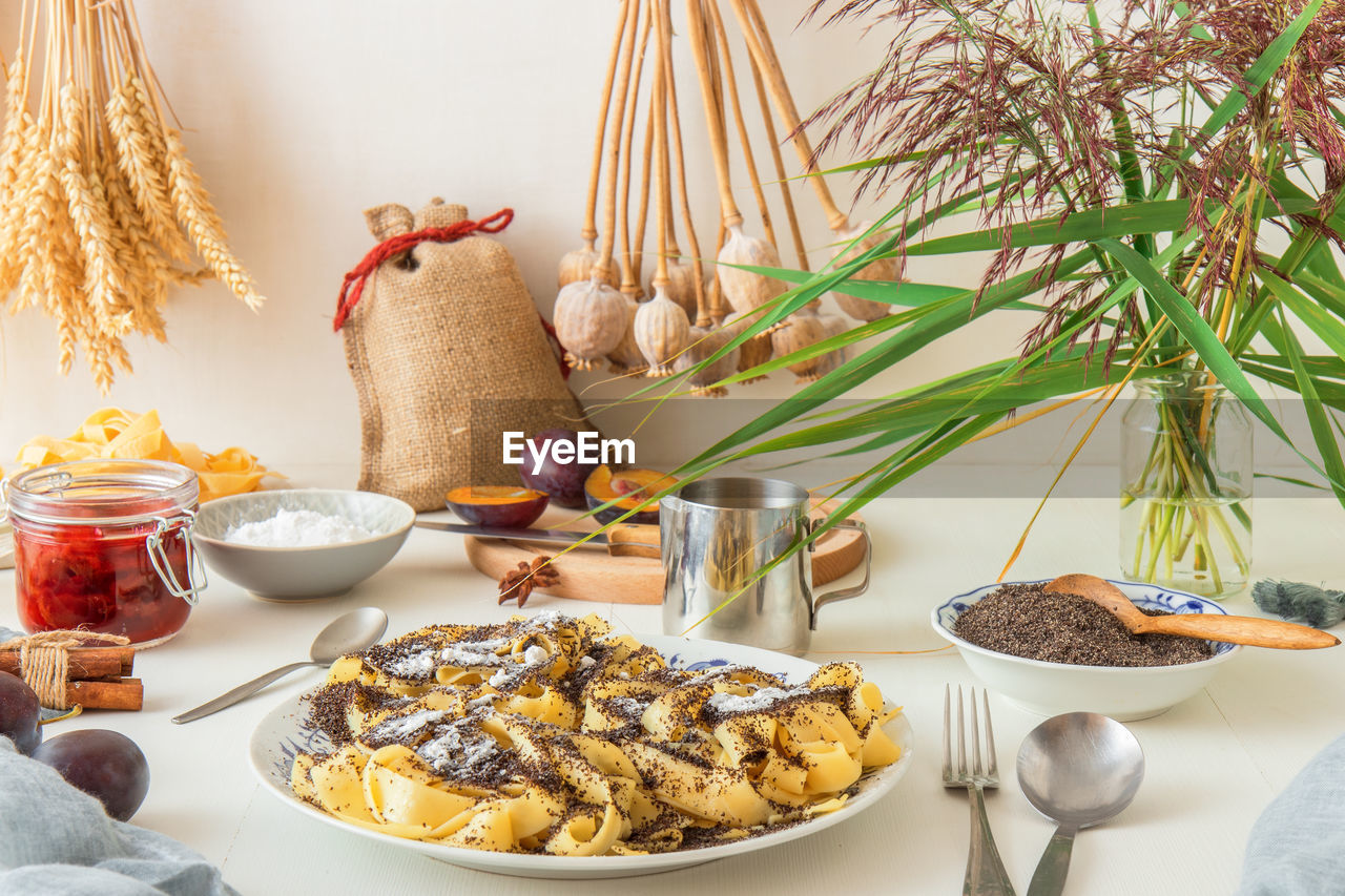 Low angle view of sweet pasta dessert, noodles with poppy seeds on white background table.