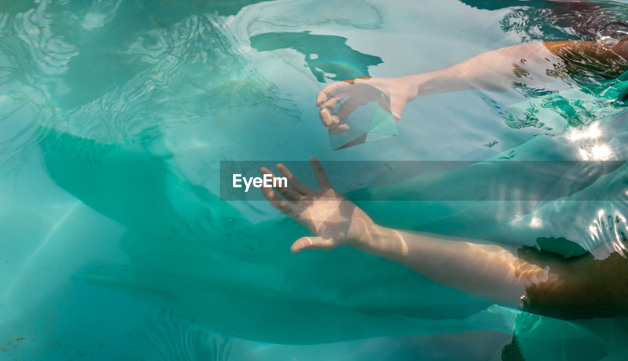 Cropped hands of woman holding prism in swimming pool