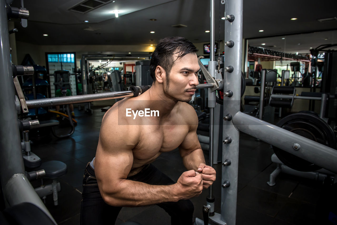 Shirtless muscular man flexing muscles in gym