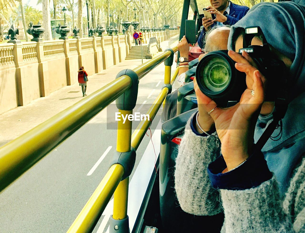 MAN PHOTOGRAPHING WOMAN HOLDING CAMERA WHILE STANDING ON CABLE