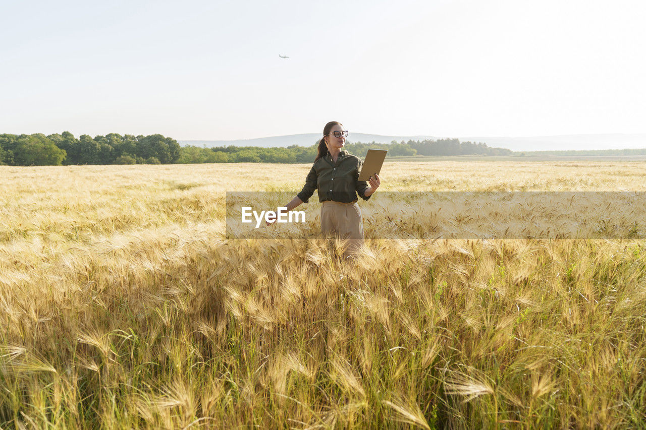 Agronomist using tablet pc standing in barley field