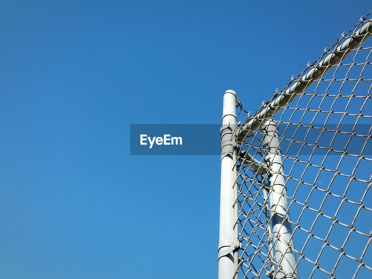 LOW ANGLE VIEW OF BASKETBALL HOOP AGAINST BLUE SKY