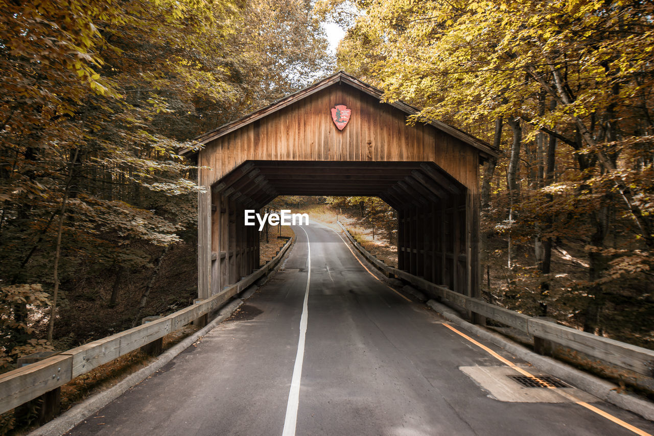 View of empty road and wooden tunnel