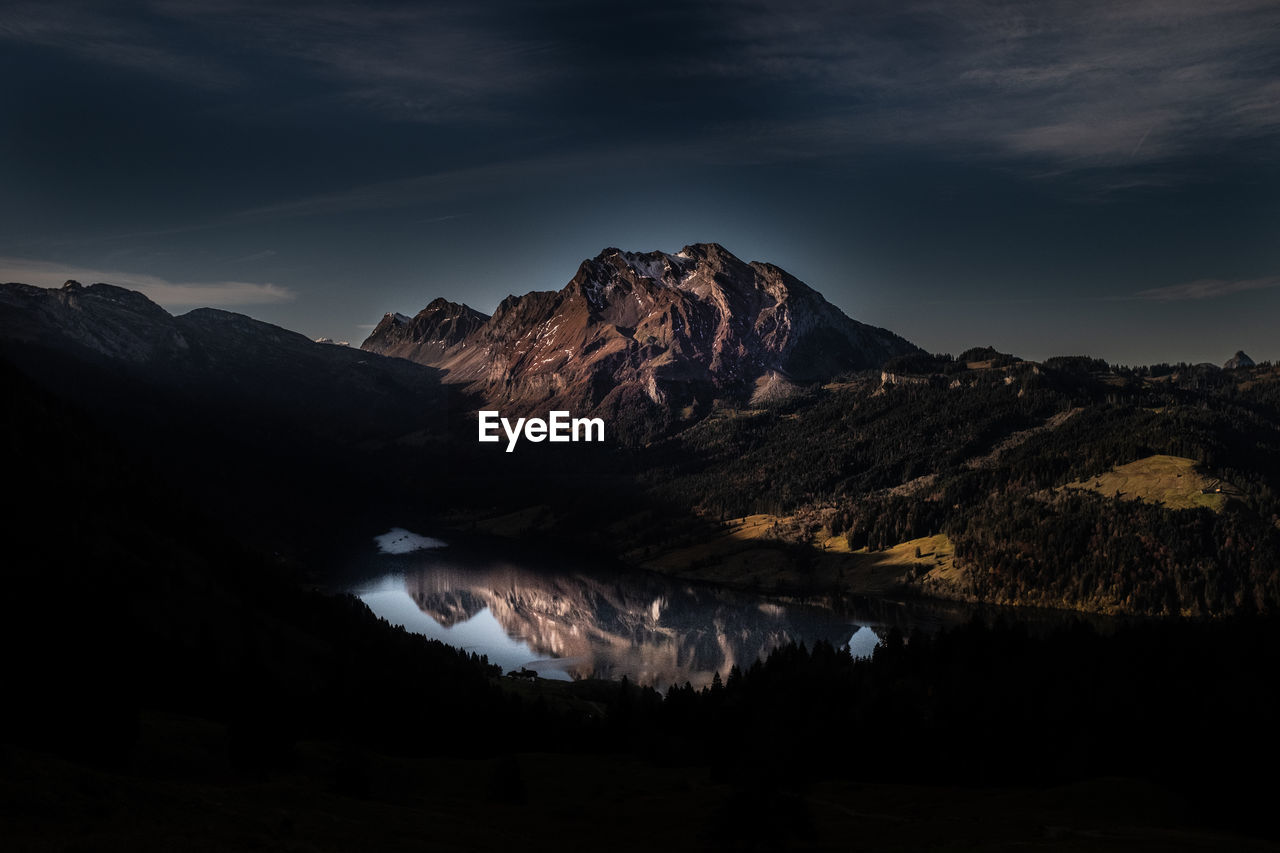 Scenic view of lake and mountains against sky at night