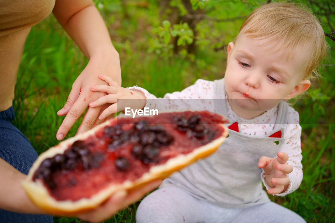 Mother and daughter eat jam bread at a picnic spring