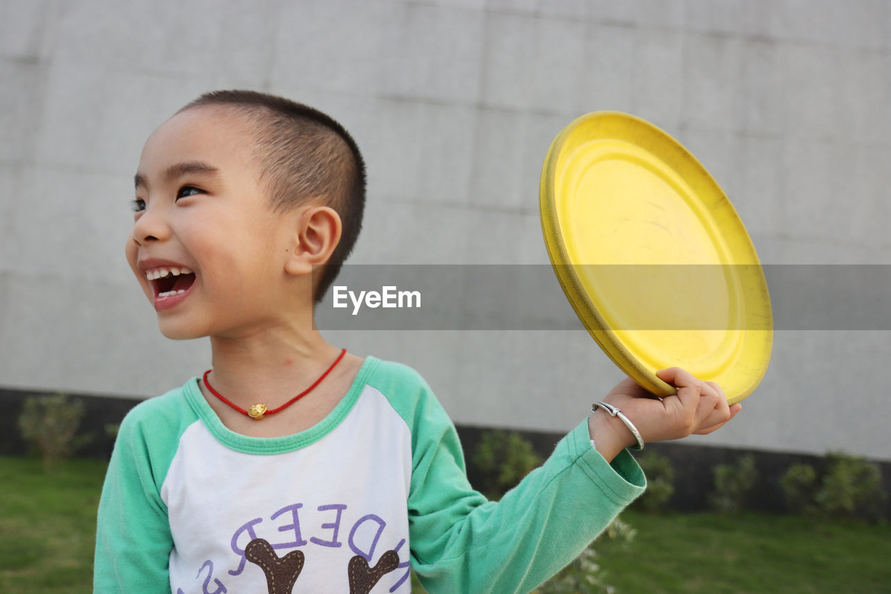 Cheerful boy playing with plastic disc at park