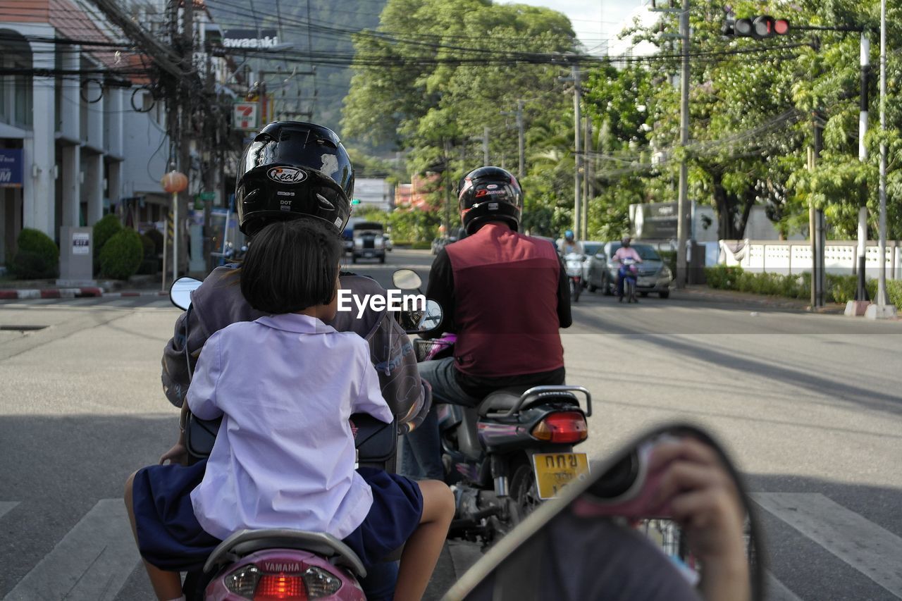 REAR VIEW OF PEOPLE RIDING BICYCLE ON ROAD