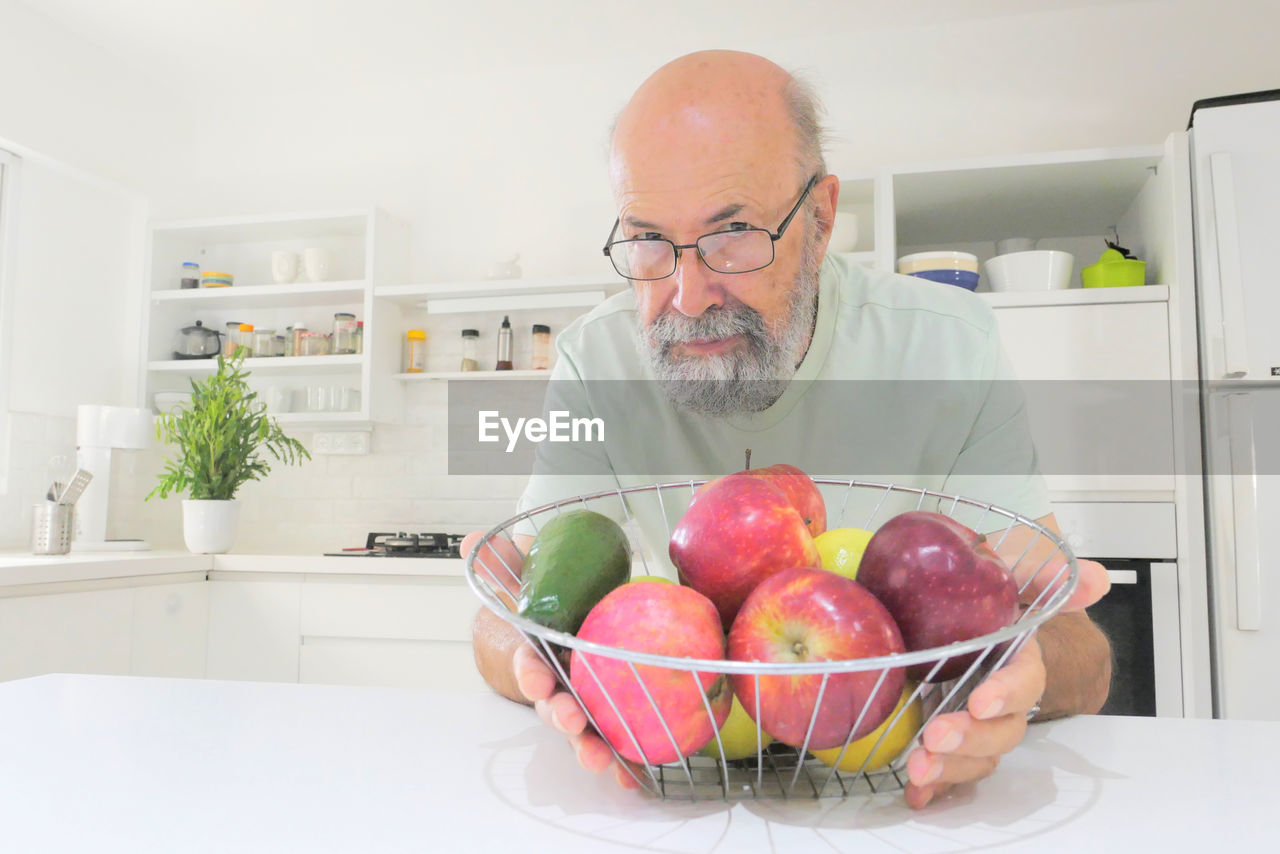 MIDSECTION OF MAN HOLDING FRUITS IN PLATE