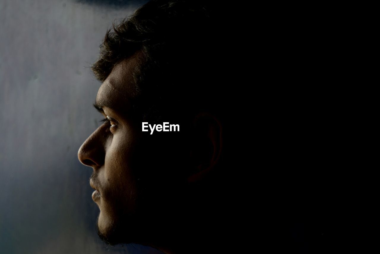 Close-up of thoughtful man looking away in darkroom