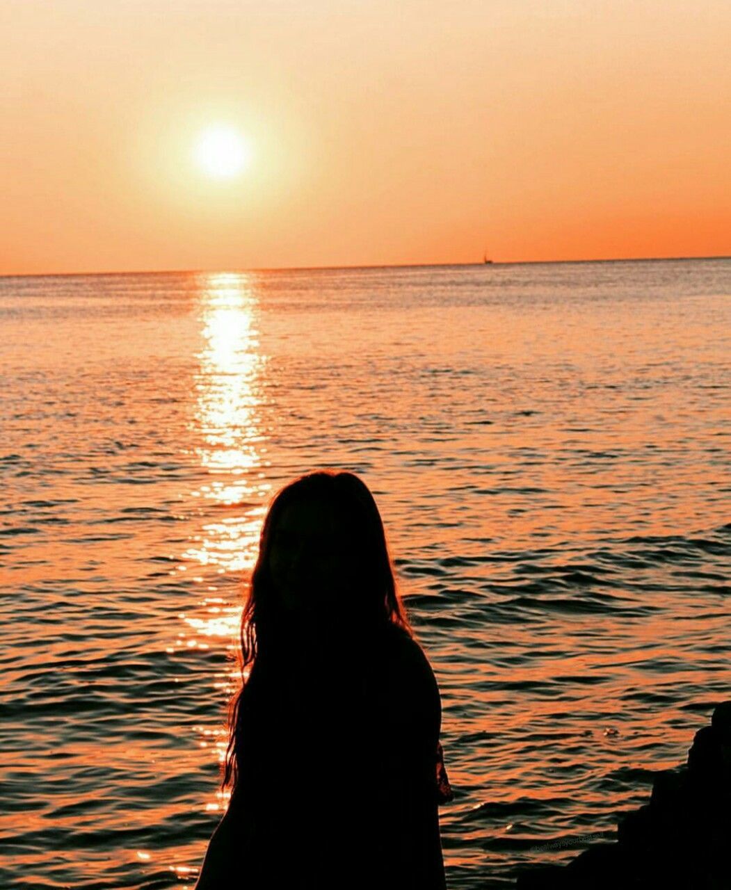 Woman at beach against sky during sunset