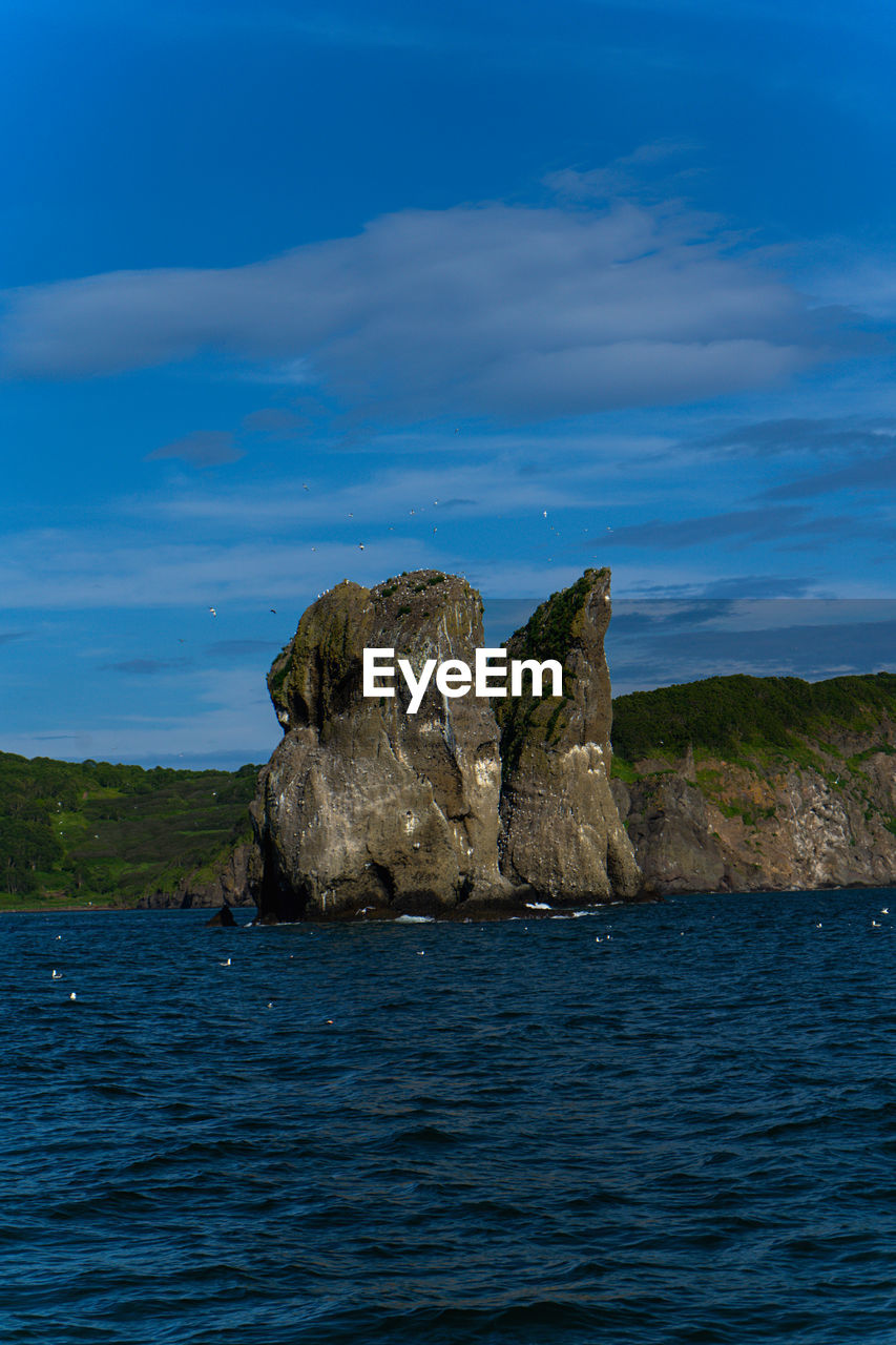 ROCKS IN SEA AGAINST BLUE SKY