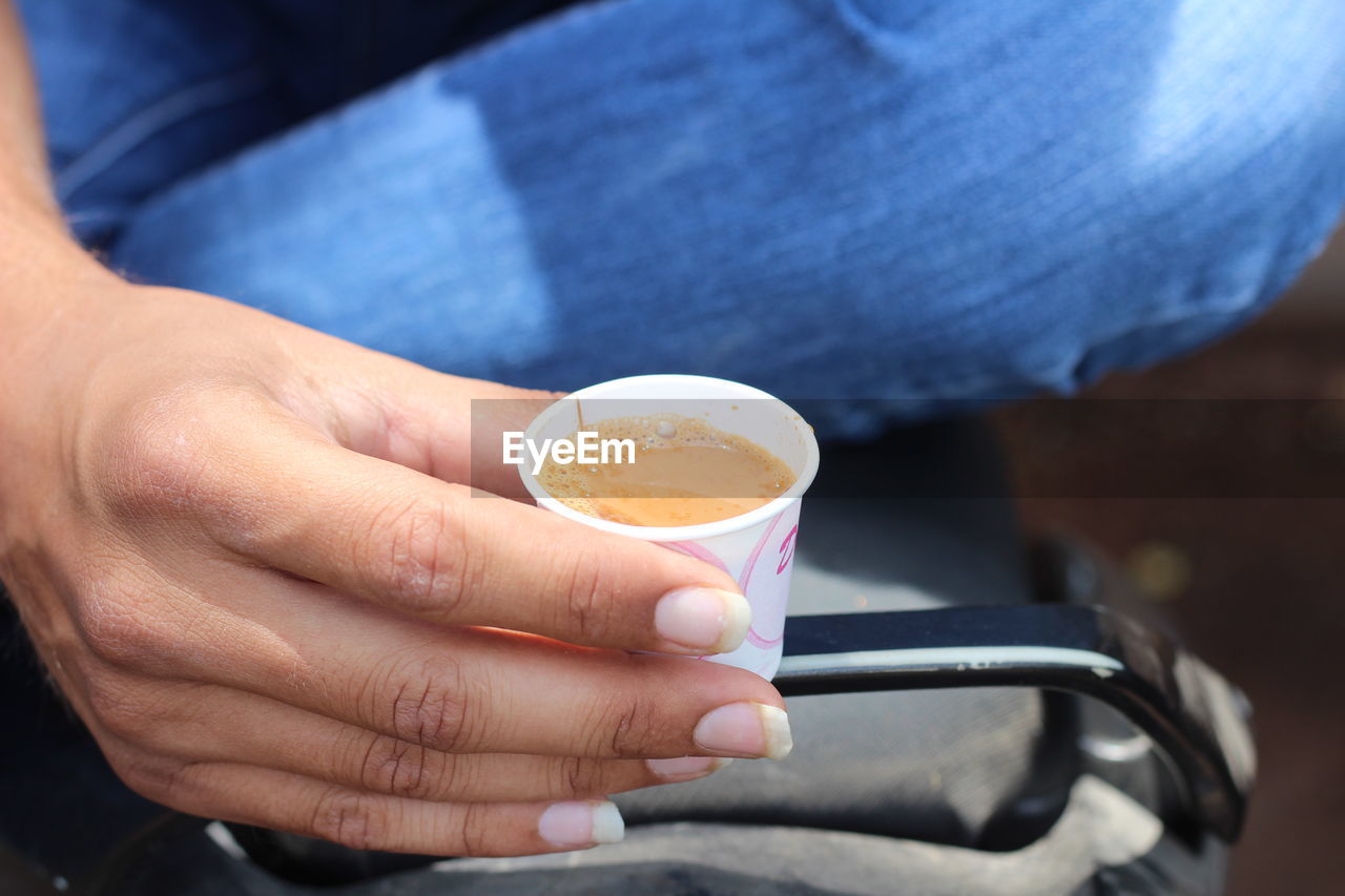 CLOSE-UP OF HAND HOLDING COFFEE