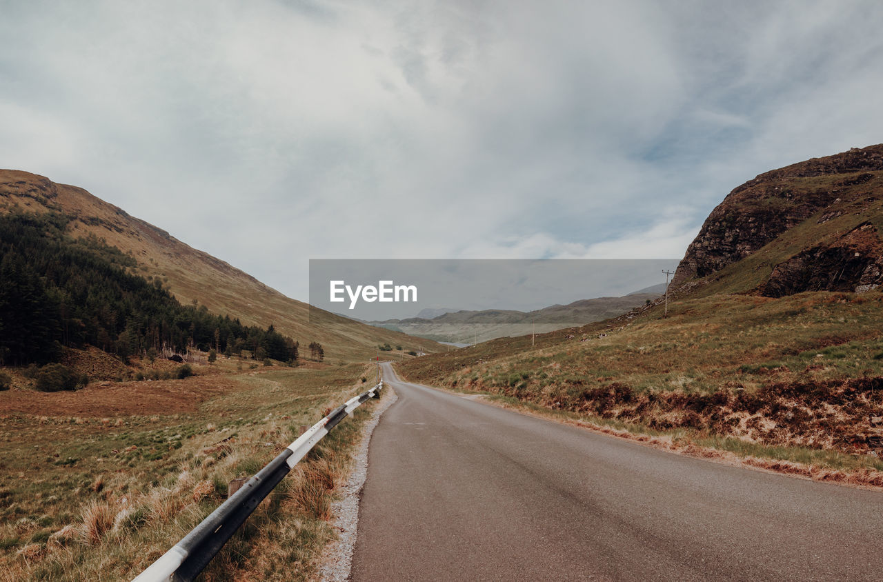 Road leading towards mountains against sky