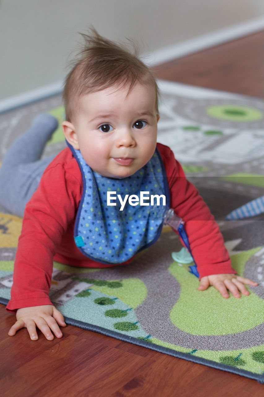 Portrait of cute baby lying on carpet at home