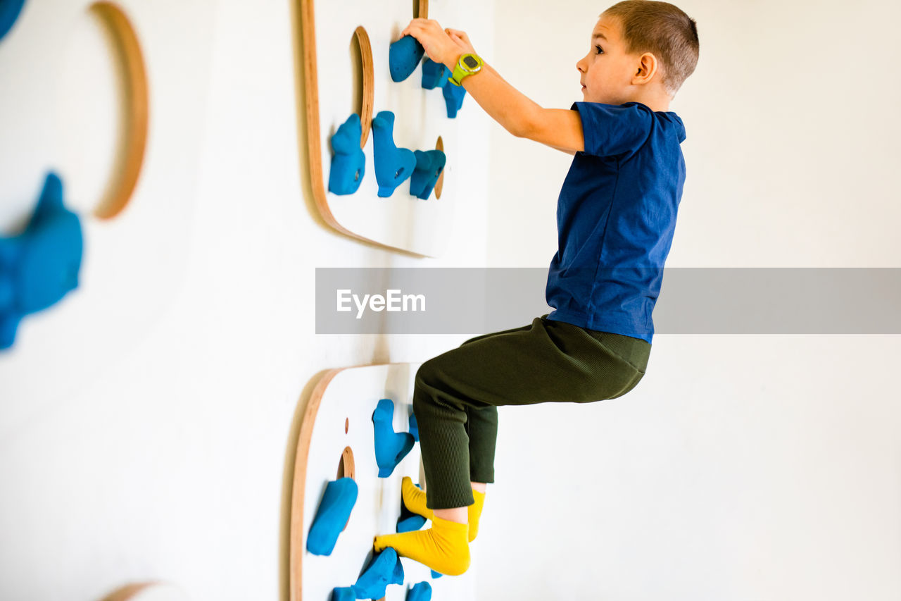 Side view of shirtless boy against wall