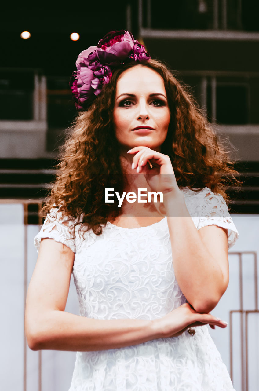 PORTRAIT OF A BEAUTIFUL YOUNG WOMAN STANDING AGAINST WALL