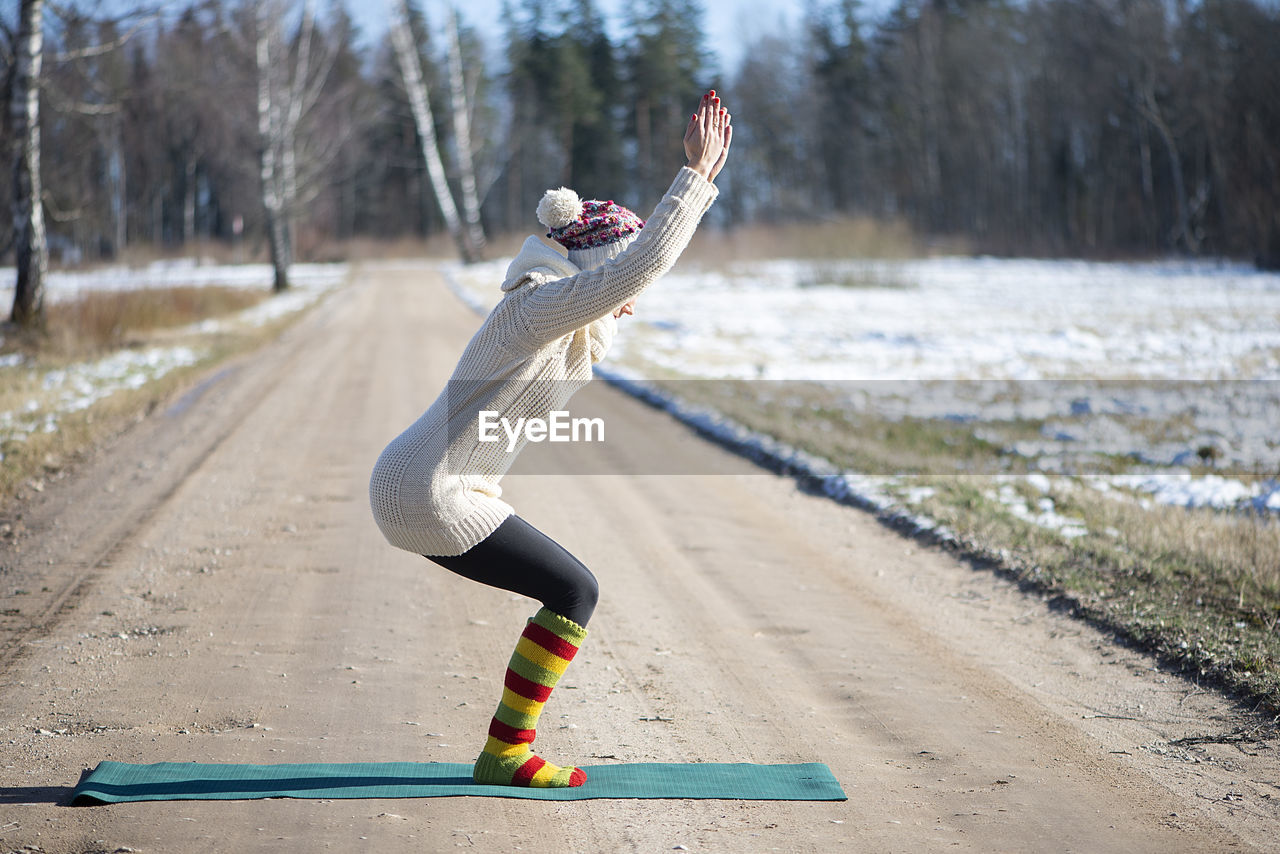 Young attractive woman practicing yoga on the rural road.outdoor activity. practice yoga asana. 