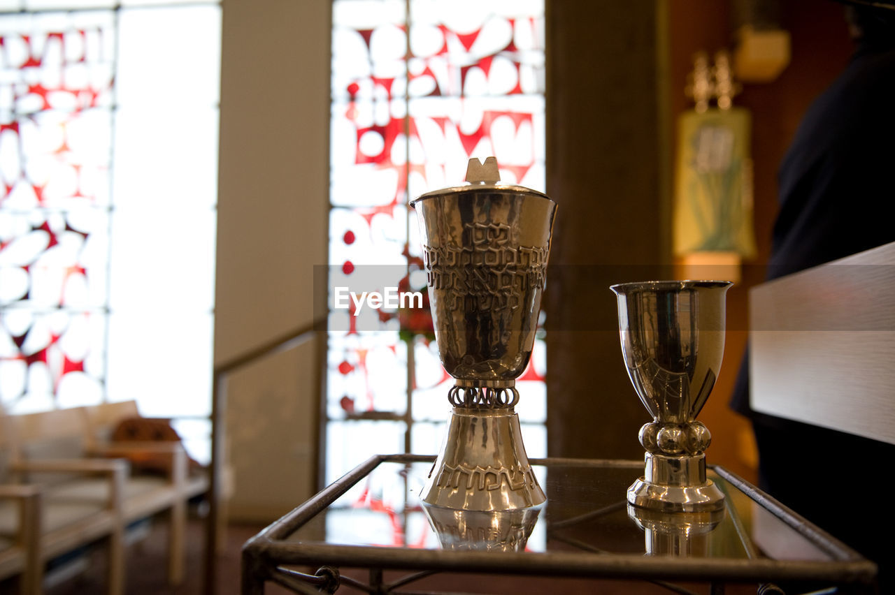 Close-up of antique chalices on glass table