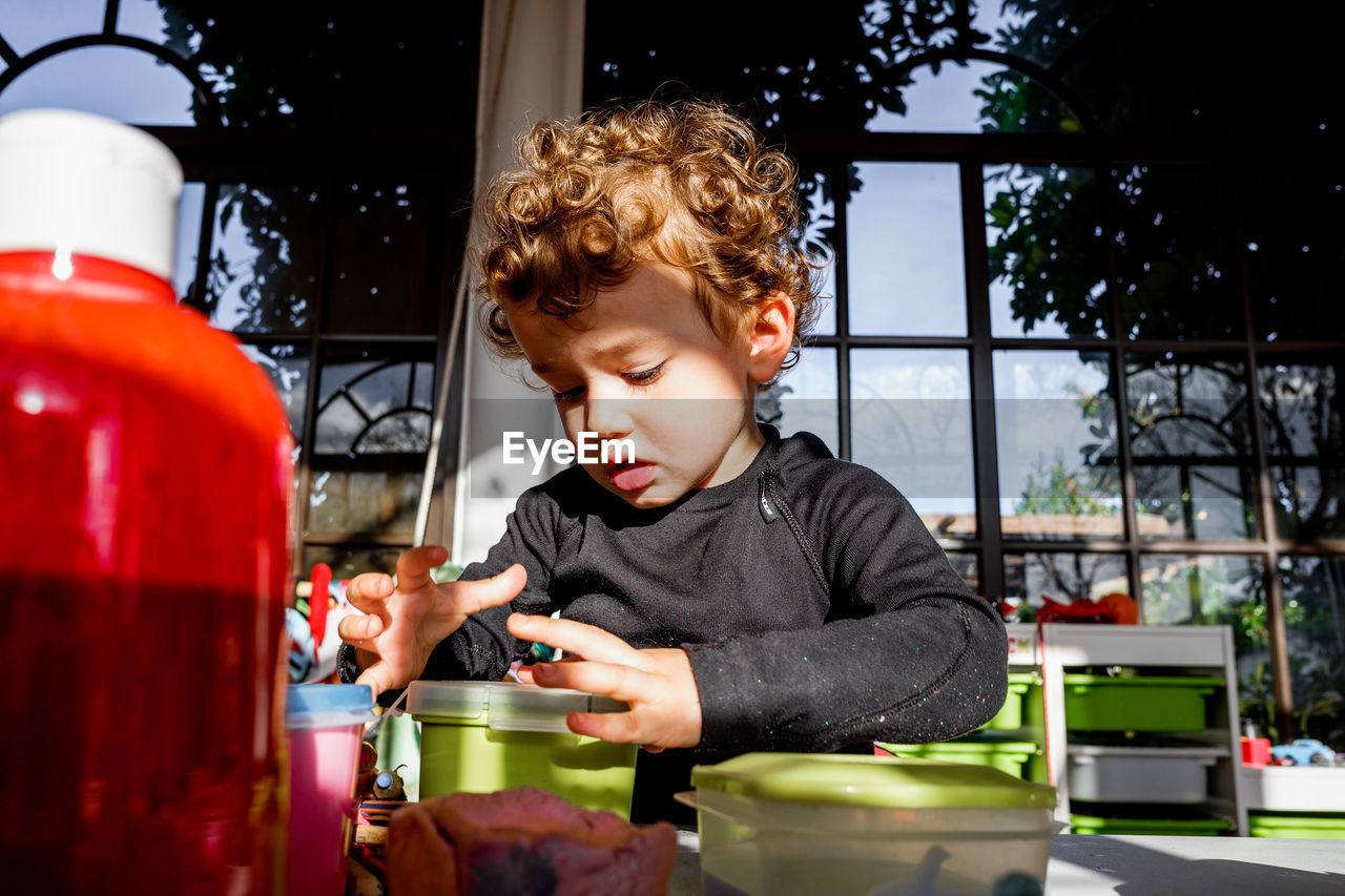 Cute girl holding plastic container while sitting at montessori