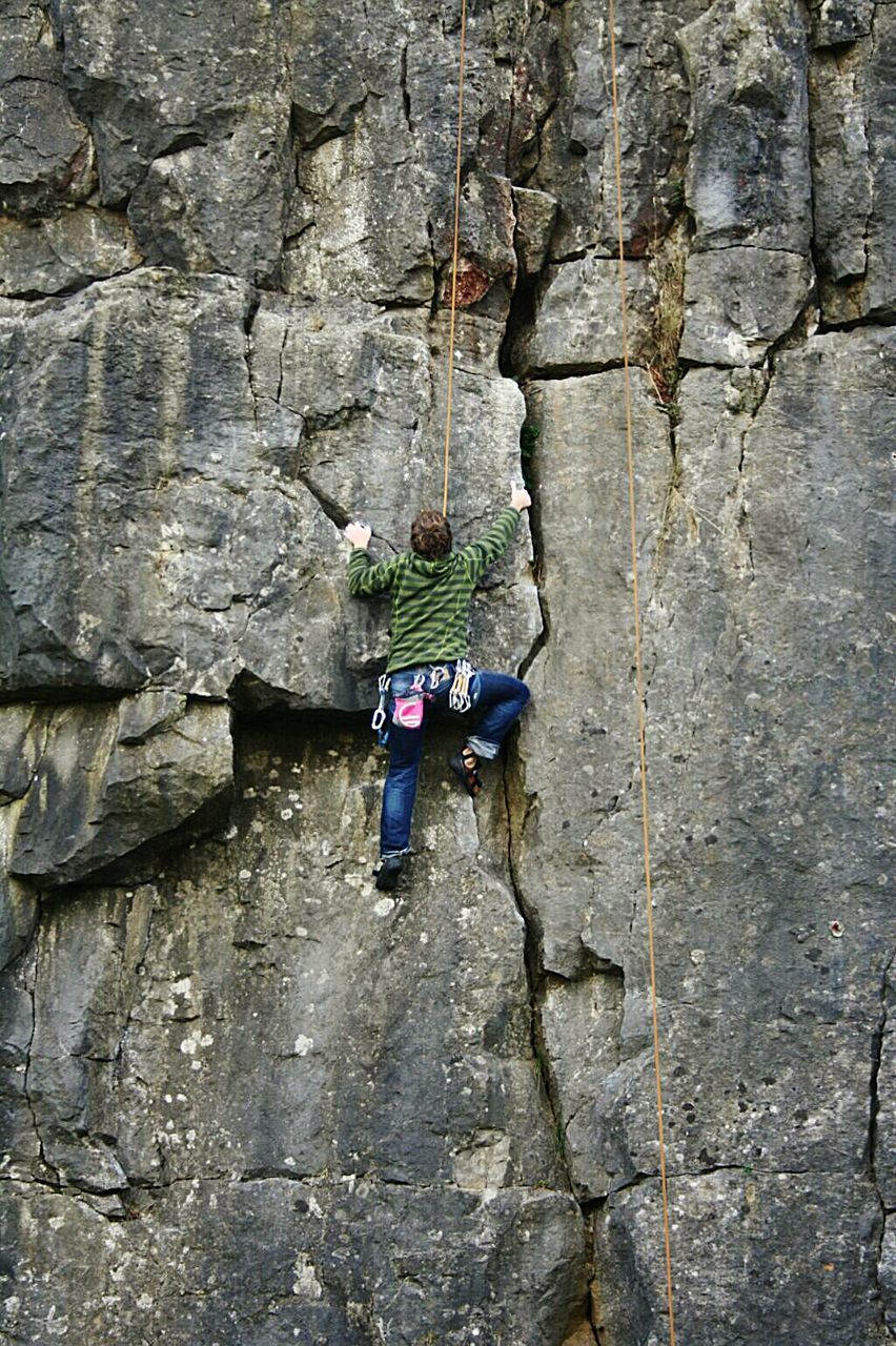 Rear view of man climbing on rock