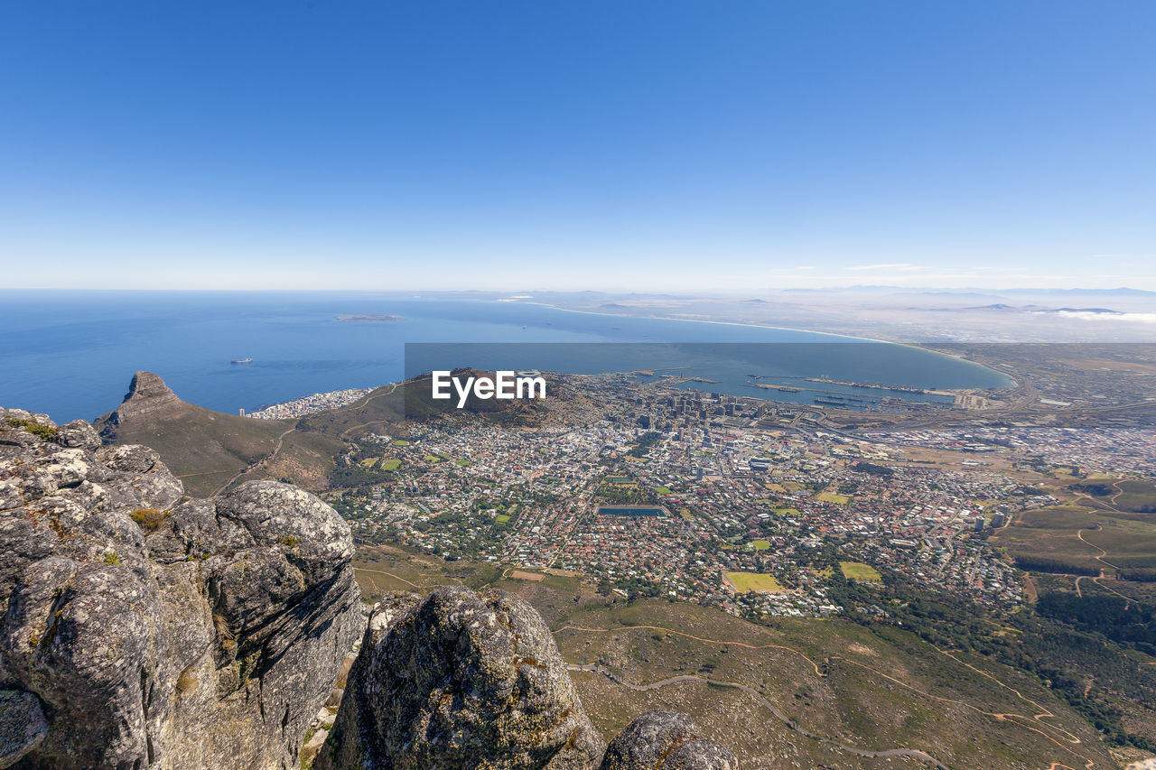 Aerial view of sea and cityscape against blue sky