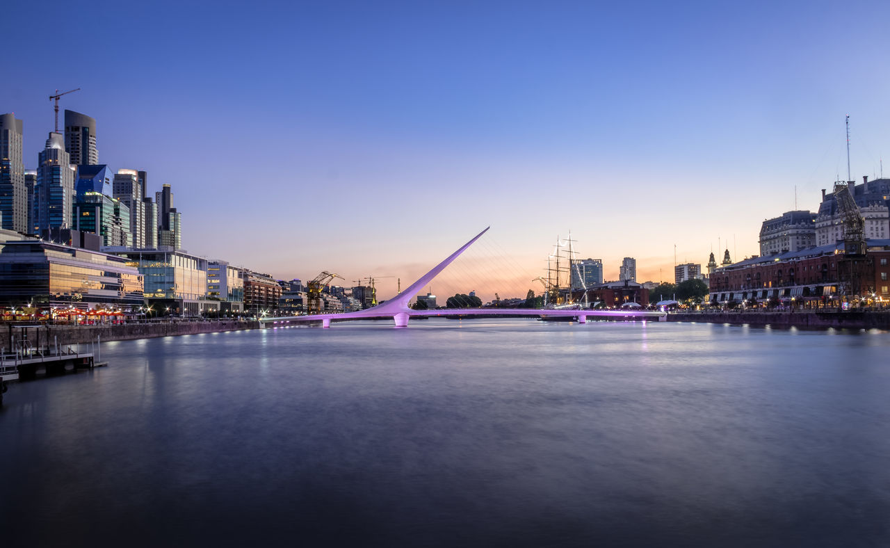 bridge over river in city against clear sky