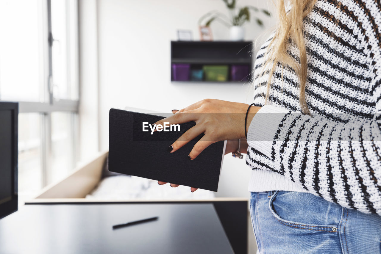 midsection of woman using digital tablet while standing in office