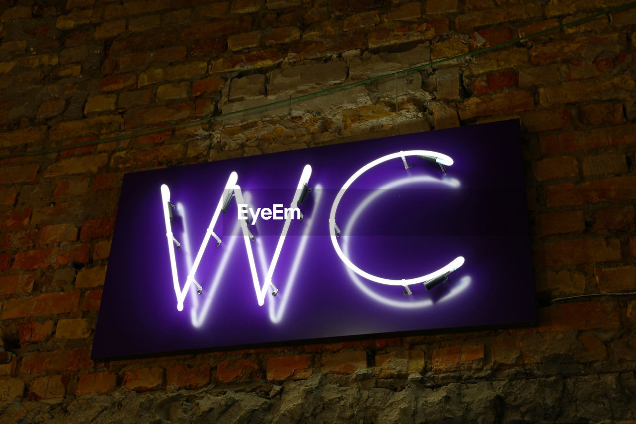 LOW ANGLE VIEW OF ILLUMINATED TEXT AGAINST WALL