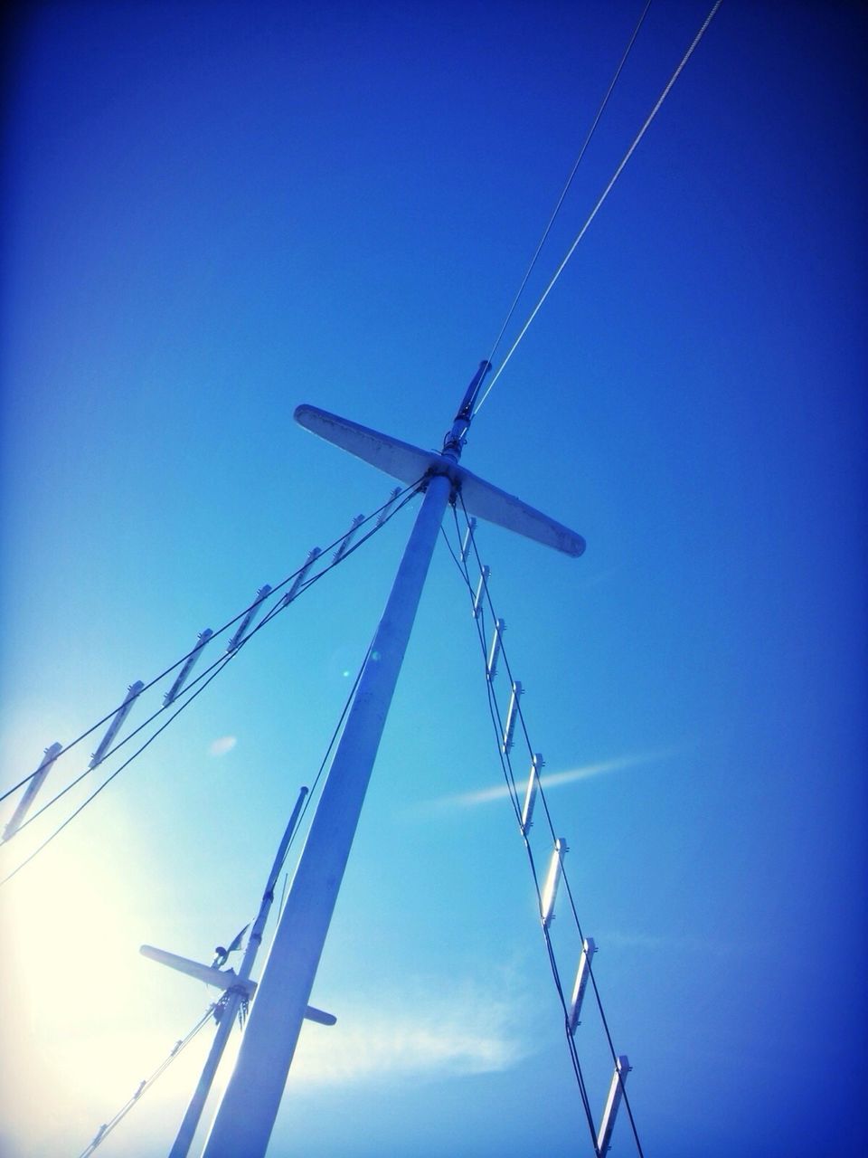 Low angle view of sailboat mast against clear blue sky