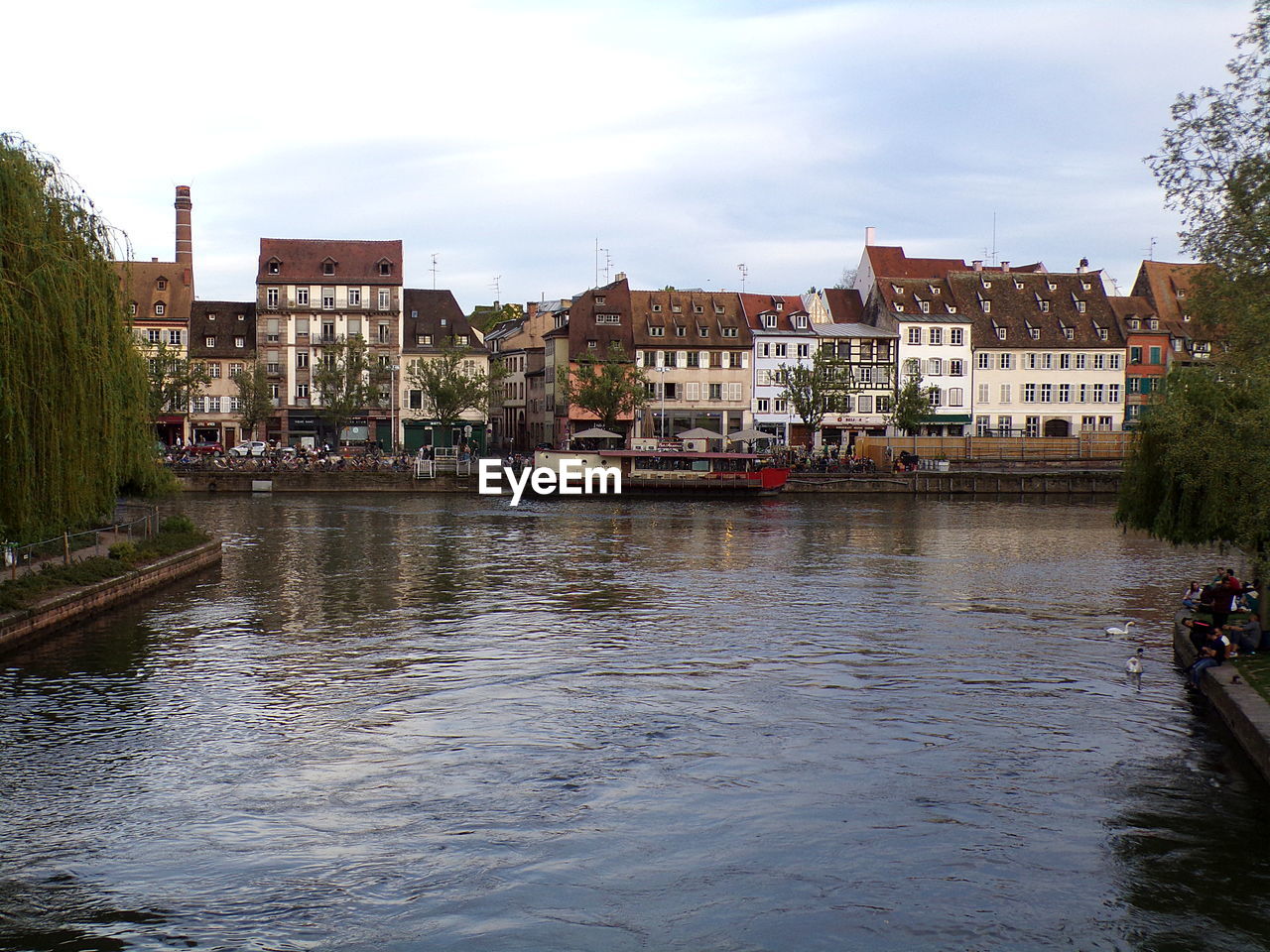 RIVER BY BUILDINGS AGAINST SKY