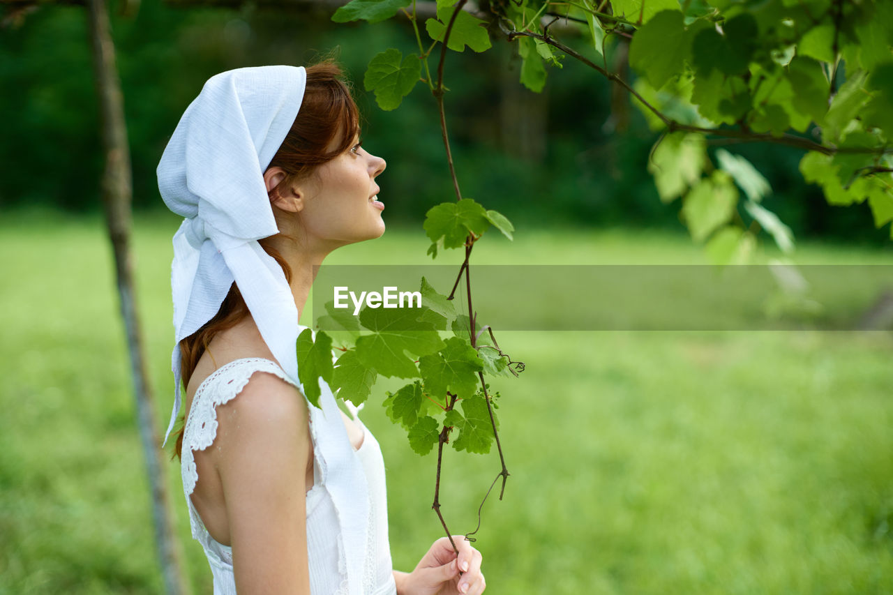 Side view of woman standing by plant