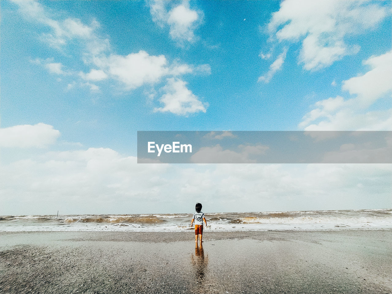 REAR VIEW OF PERSON STANDING ON BEACH