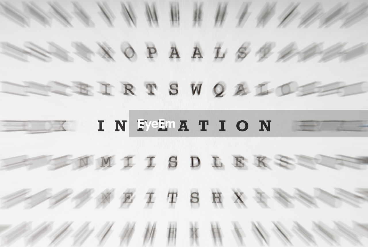 Word inflation in a puzzle or cross word riddle letter grid, focus motion blur effect 