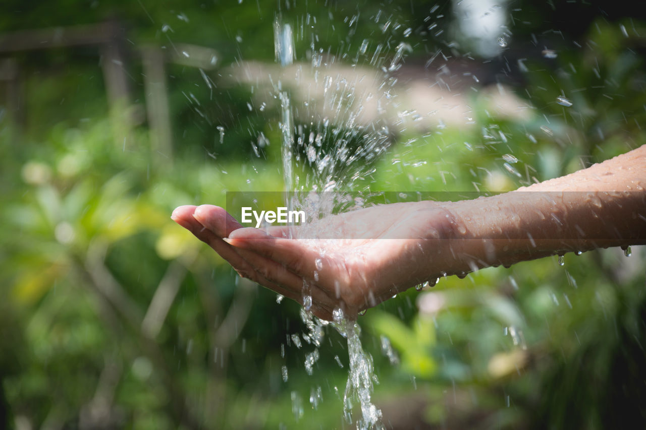 Cropped hand of woman splashing water