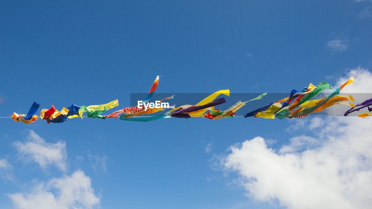 Low angle view of multi colored flags hanging against sky