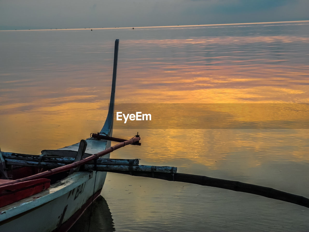 Boat moored in sea against sky during sunset