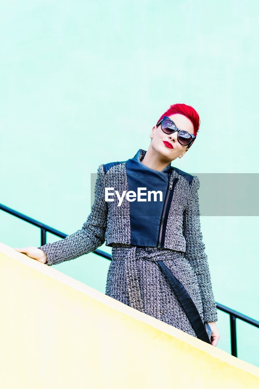 Low angle view of young woman standing by railing