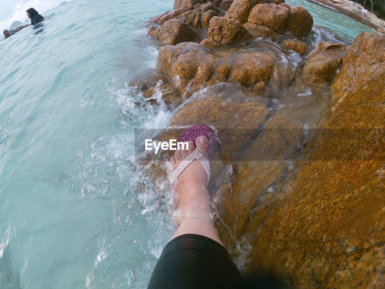 Low section of person on rock in sea