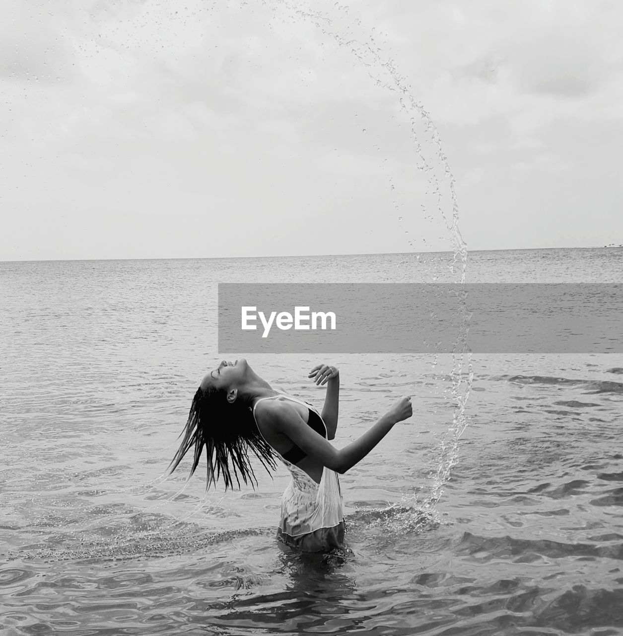 Woman standing in sea against sky