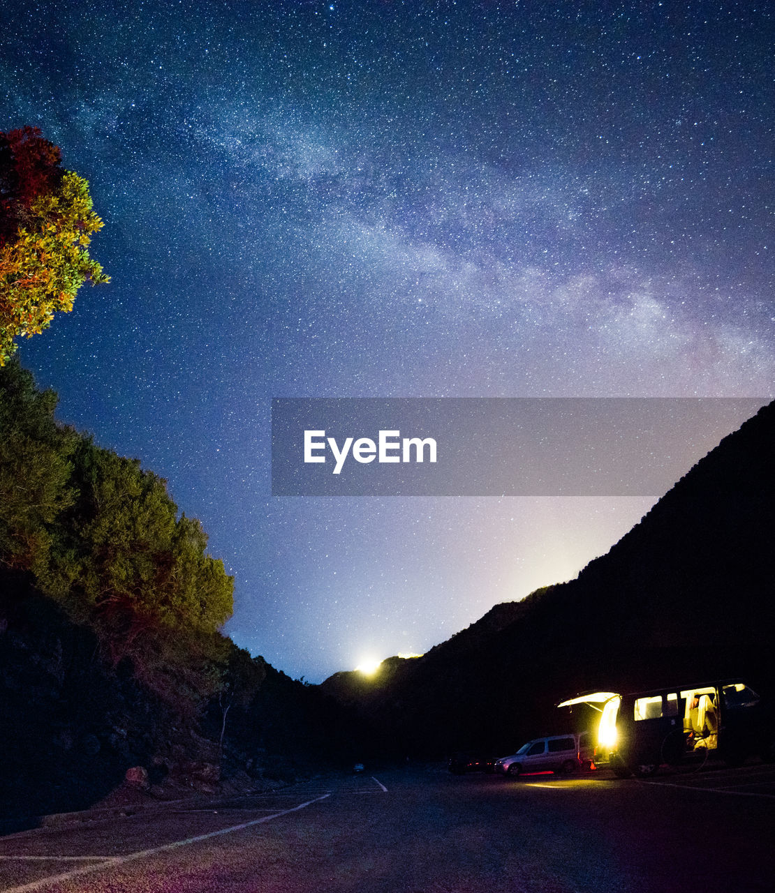 CAR ON ILLUMINATED ROAD AGAINST SKY AT NIGHT